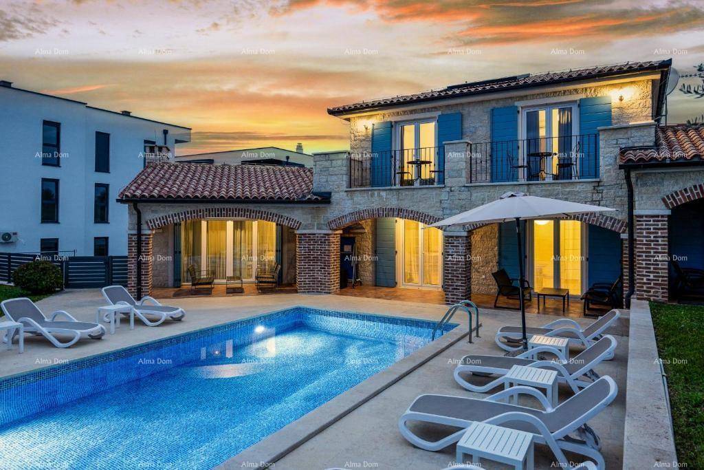 Mediterrane Villa mit beleuchtetem Pool und Sonnenliegen bei Abenddämmerung.