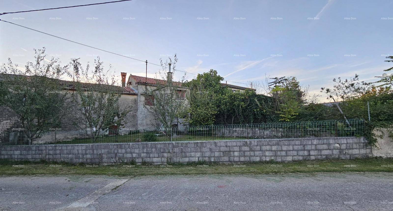 Ansicht eines älteren Wohnhauses von der Straße aus mit einem niedrigen Zaun und Bäumen im Vorgarten.