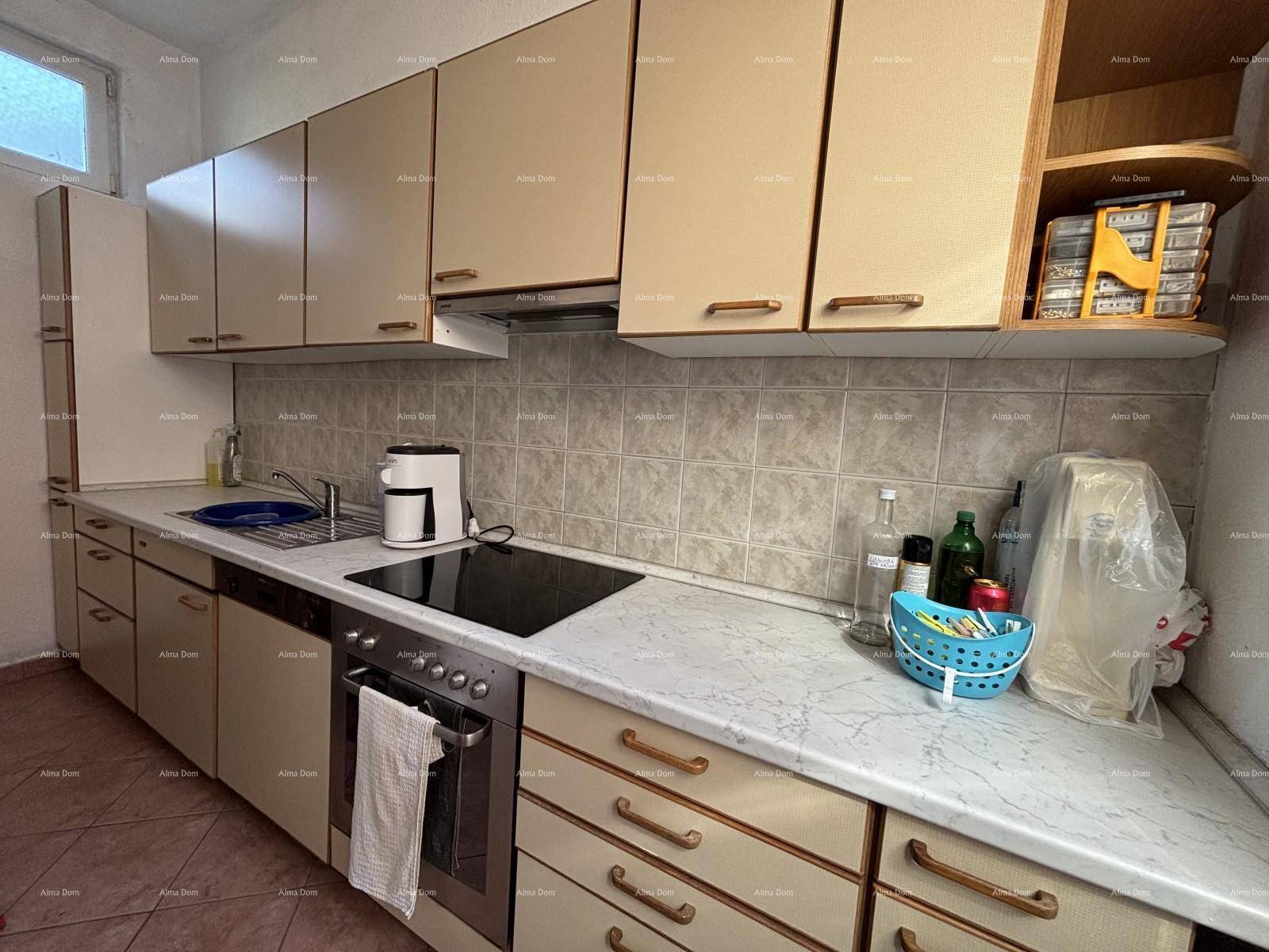 Funktionale Küche mit beigen Einbauschränken, Fliesenrückwand und integriertem Kochfeld und Backofen.