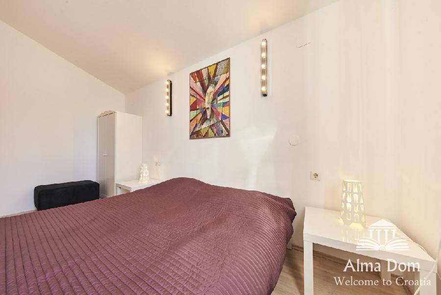 Schlafzimmer mit Doppelbett, Nachttischen und farbenfrohem Kunstwerk an der Wand.