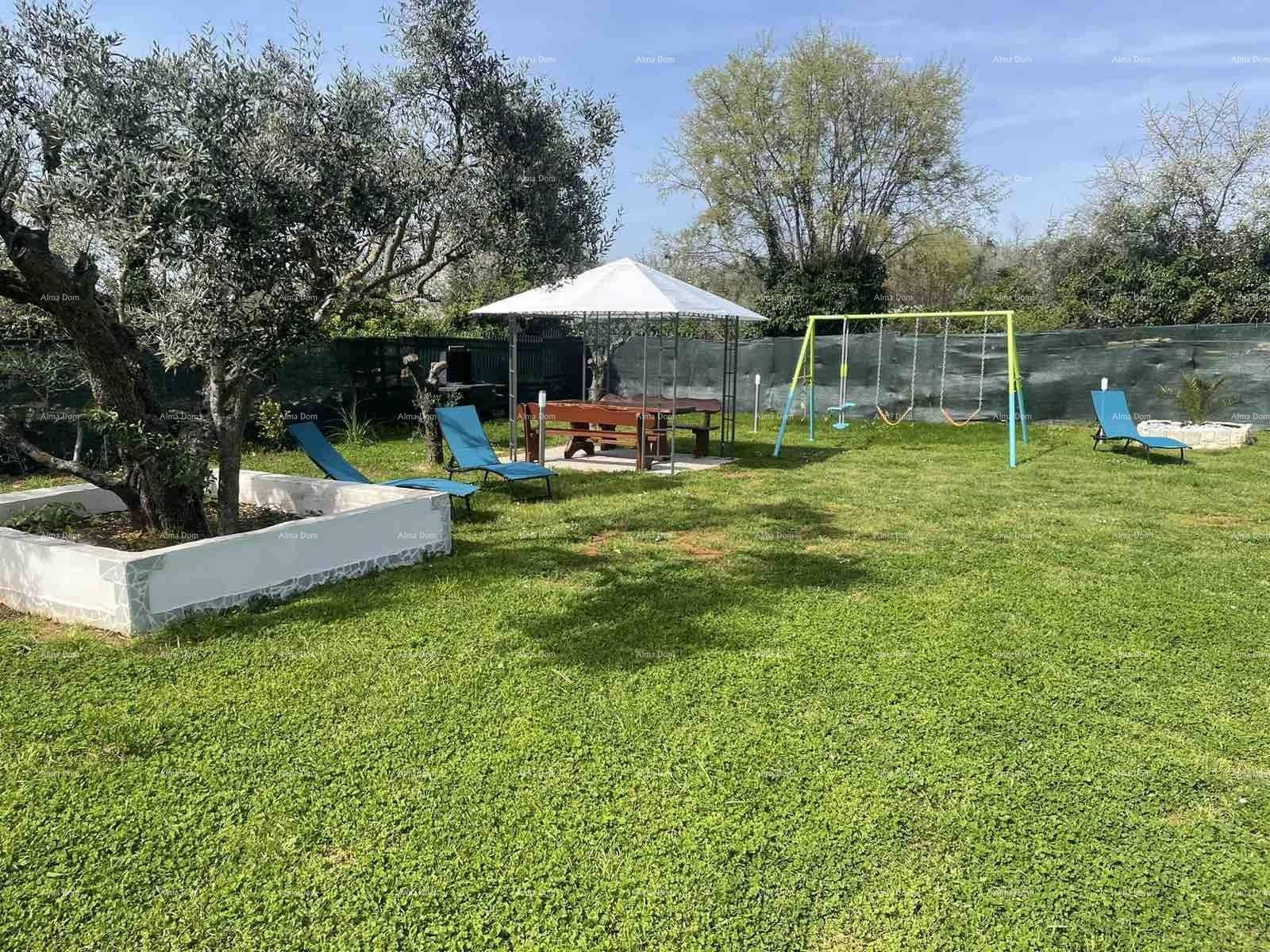 Großer, sonniger Garten mit Rasenfläche, einem Pavillon, Liegestühlen und einem Spielbereich.