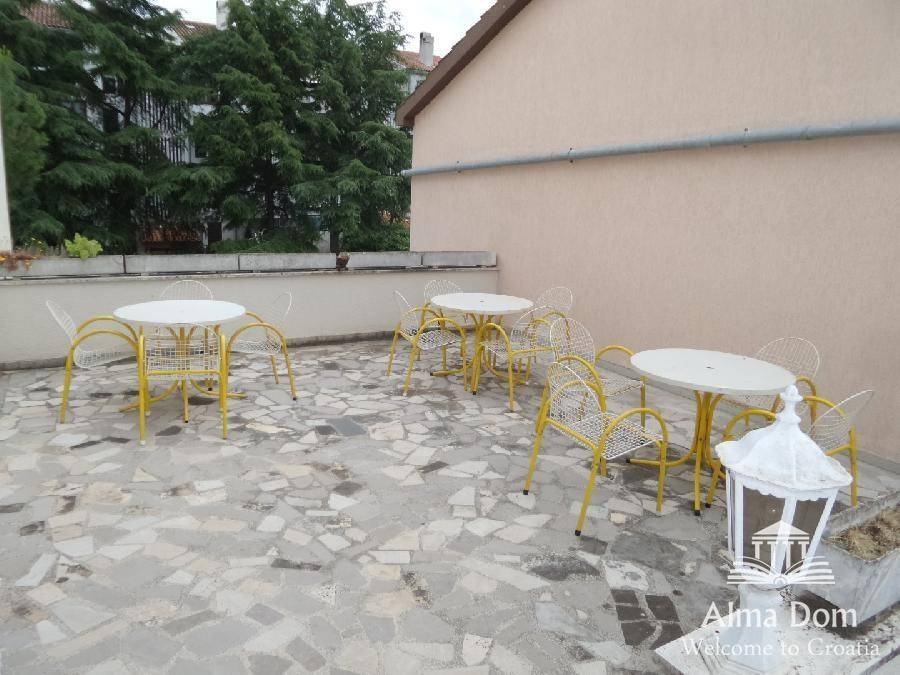 Große Dachterrasse mit mehreren Tischen und Stühlen, ideal für Mahlzeiten im Freien und Geselligkeit.