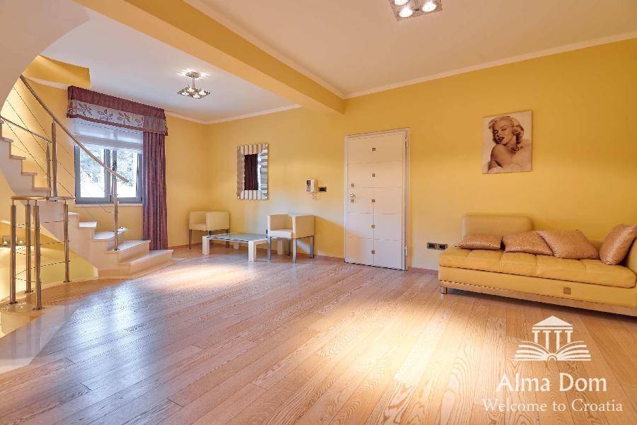 Geräumiges Wohnzimmer mit Holzboden, gelben Wänden und bequemer Sitzgelegenheit.