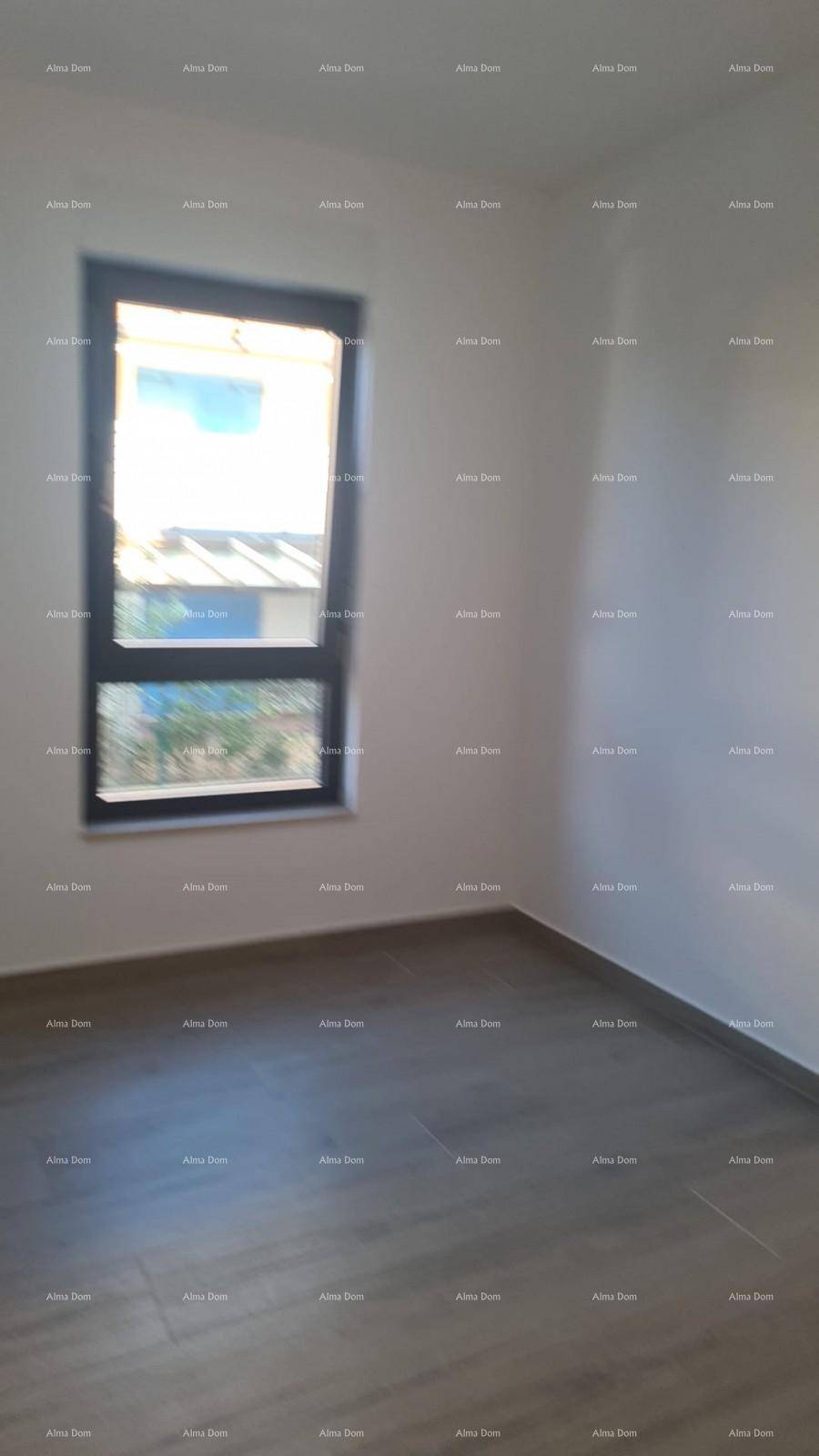 Leeres Schlafzimmer mit hellem Holzboden und einem großen Fenster, das viel Licht spendet.