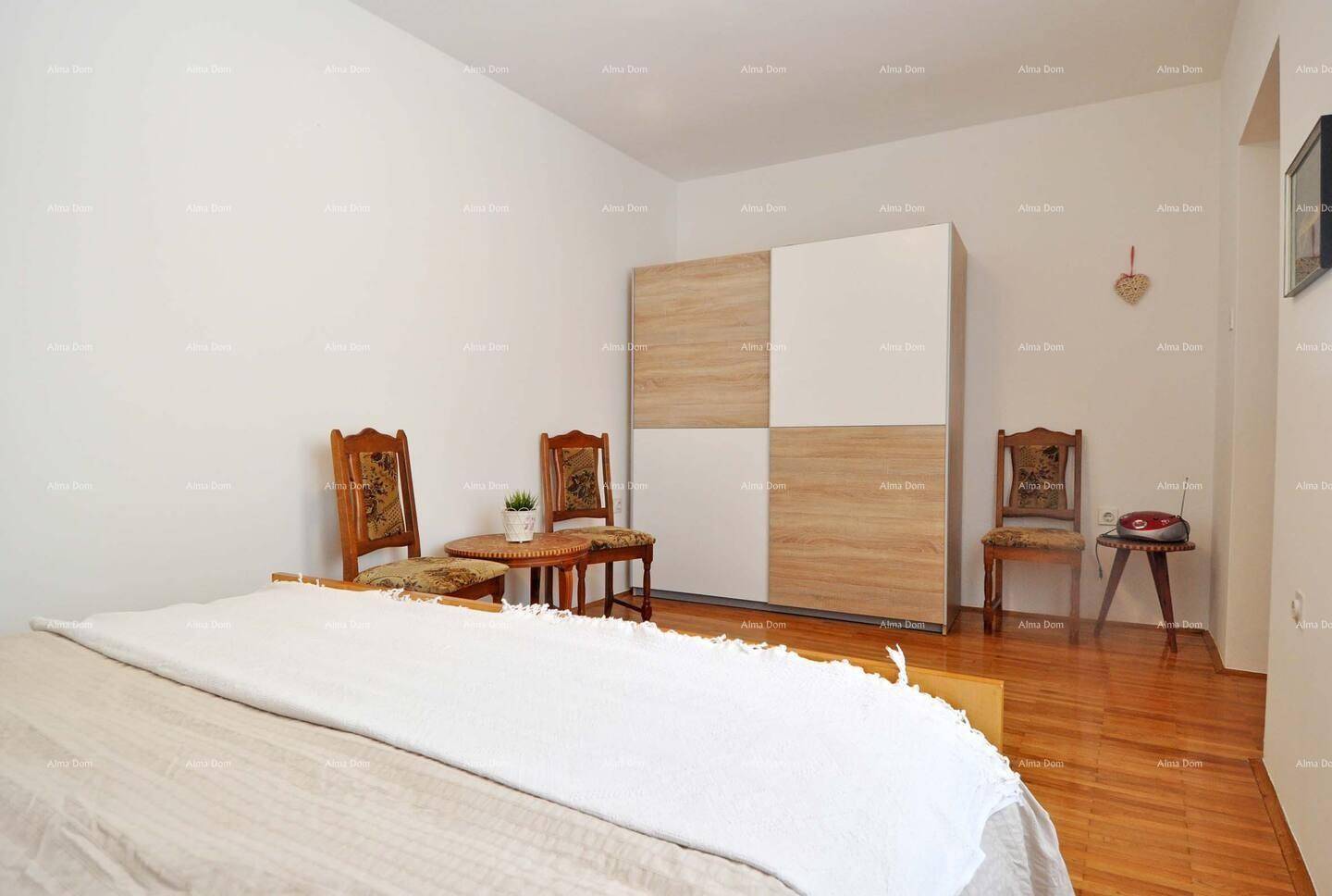 Helles Schlafzimmer mit Doppelbett, Holzschrank und Parkettboden.