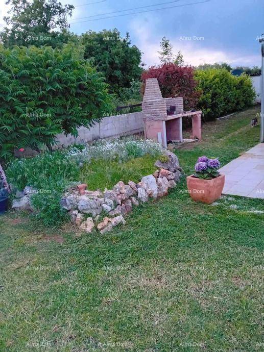 Gartenbereich mit Rasenfläche, Steinmauer und einem gemauerten Grillplatz.