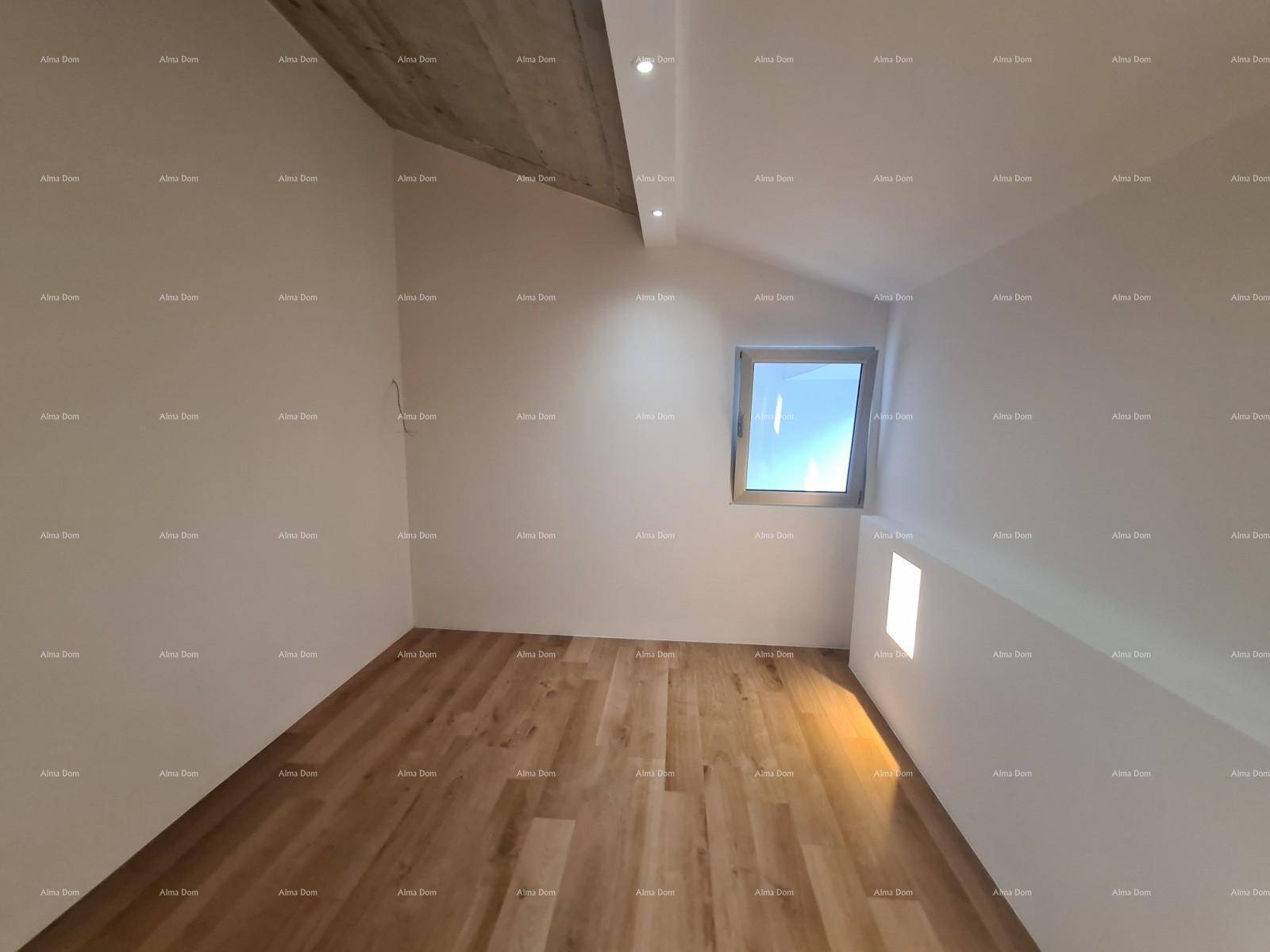 Schlafzimmer mit Holzboden, schräger Decke und einem Fenster für natürliches Licht.