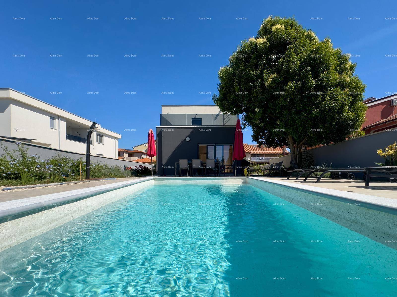 Blick über den glitzernden Pool auf die moderne Villa und den Essbereich im Freien.