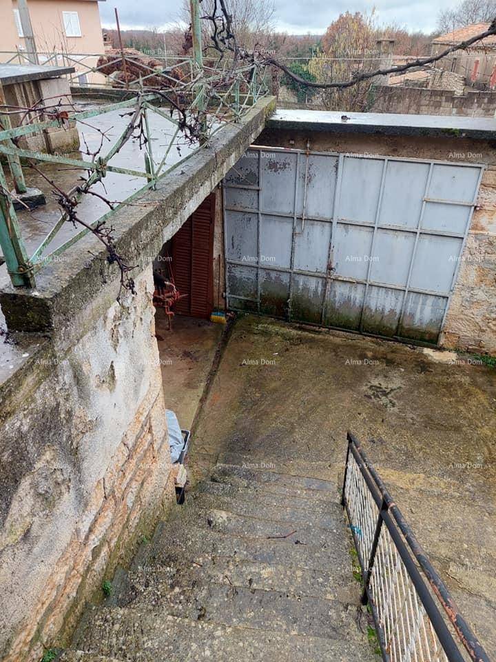 Außentreppe führt zu einer Betonterrasse mit einem Garagentor im Hintergrund, umgeben von alten Mauern.