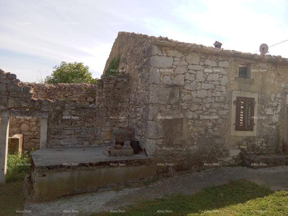 Verfallenes Steinhaus mit teilweise eingestürzten Mauern und einem alten Fensterladen in ländlicher Umgebung.
