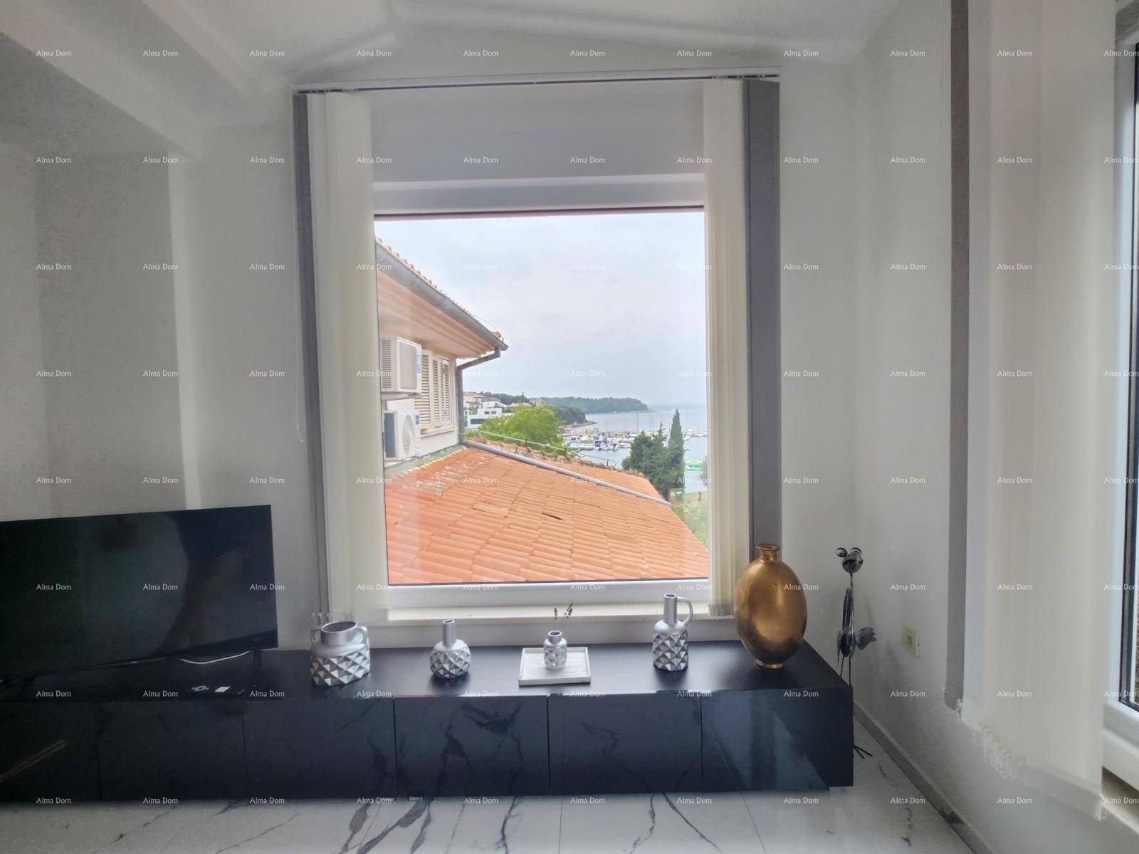 Wohnzimmer mit Fensterblick auf ein Ziegeldach, den Hafen und das Meer in der Ferne.