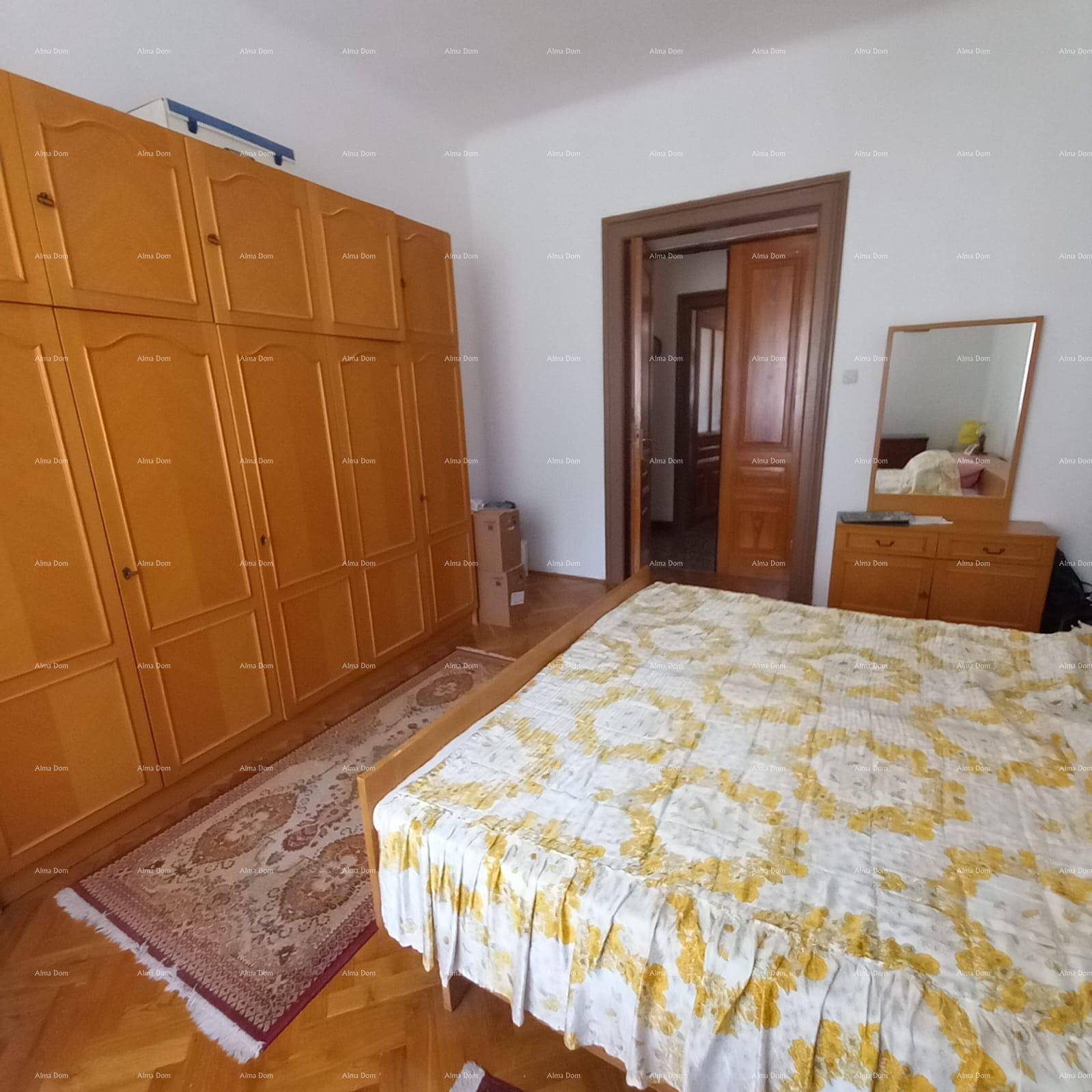 Geräumiges Schlafzimmer mit Doppelbett, Holzschrank und Parkettboden.