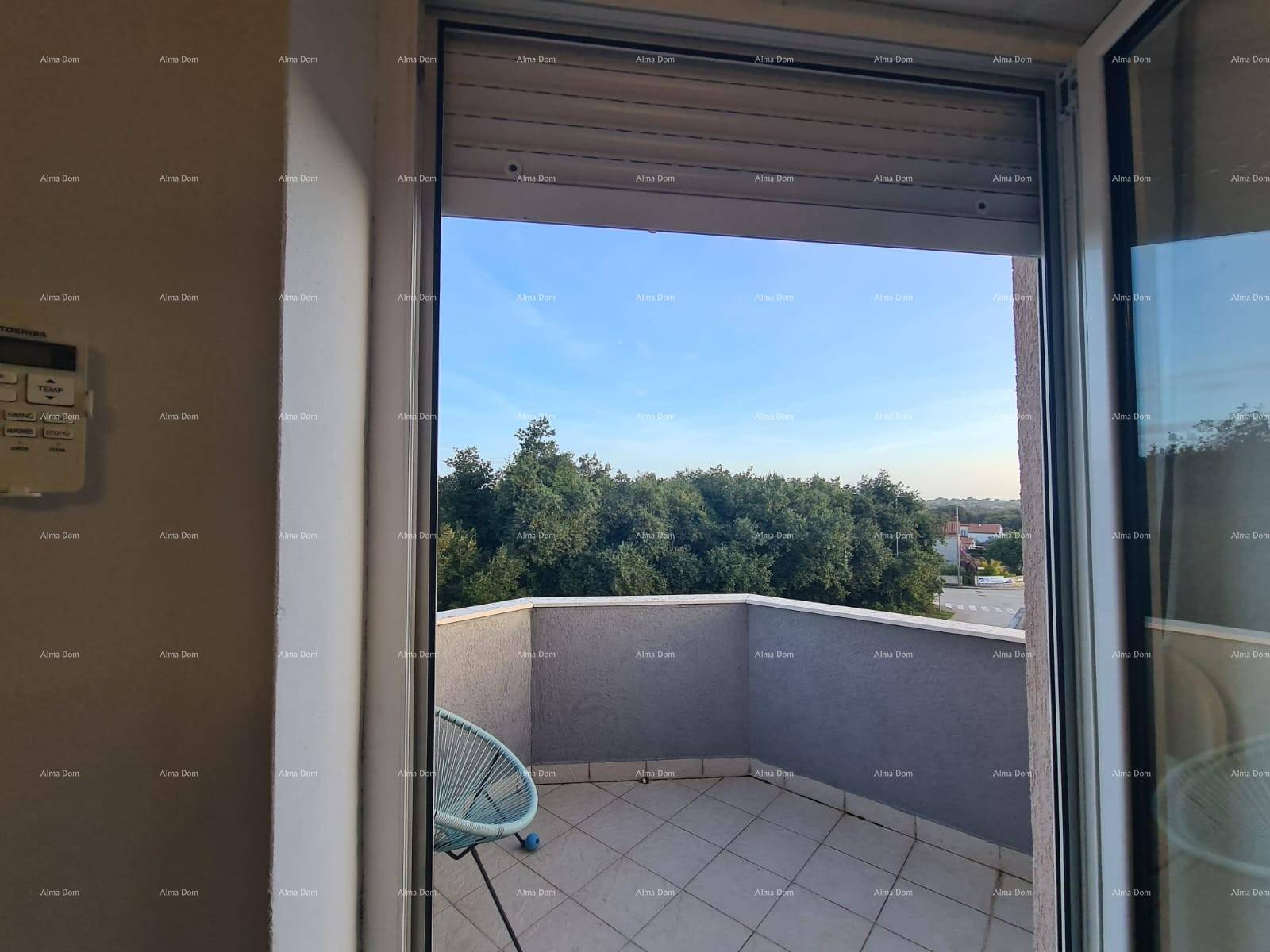 Blick vom Wohnzimmer auf den Balkon mit grüner Umgebung und weitem Himmel.