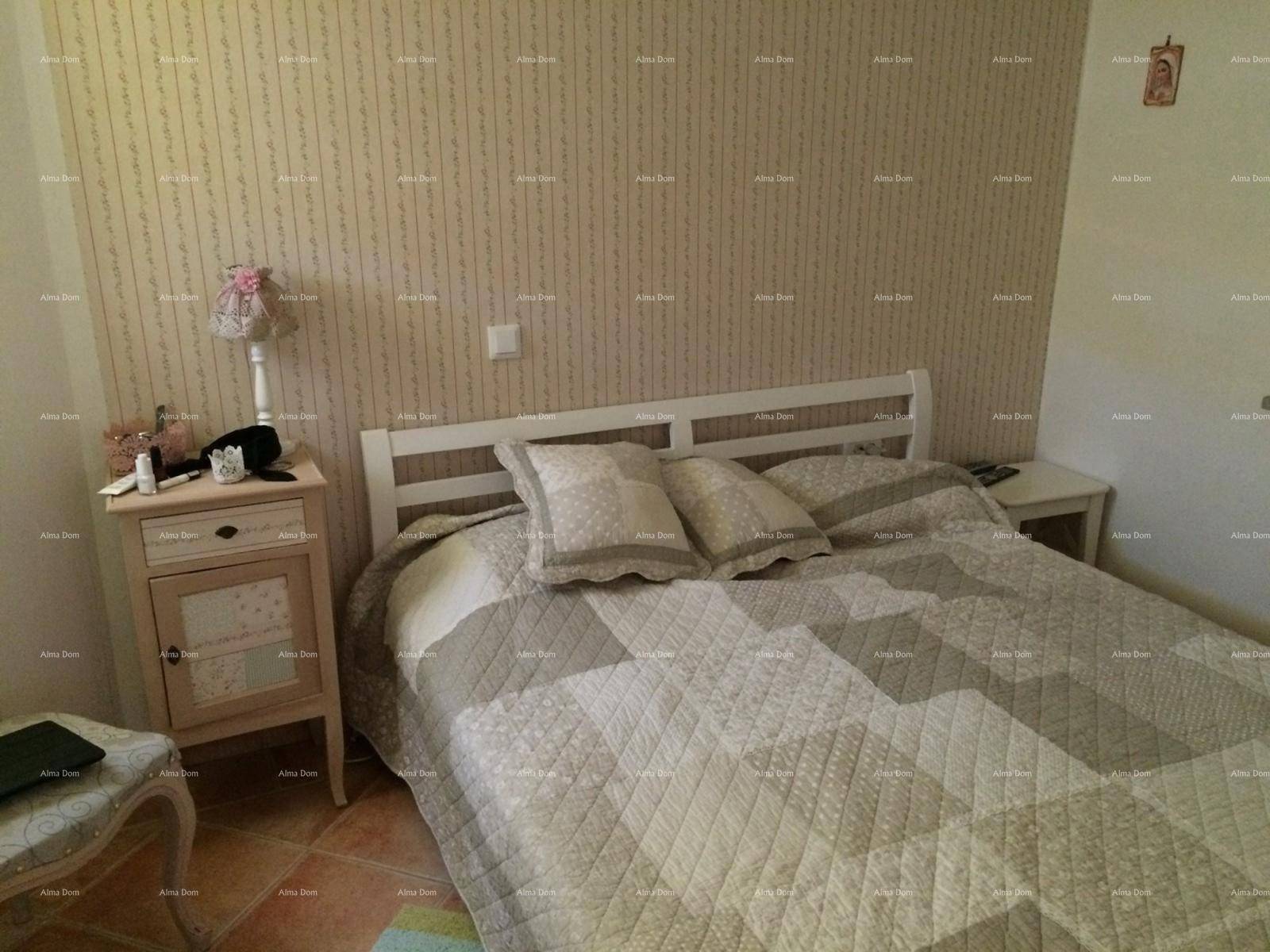 Schlafzimmer mit Doppelbett, Nachttisch und gemusterter Tapete.