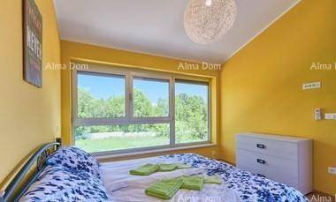Helles Schlafzimmer mit gelben Wänden, Doppelbett und großem Fenster mit Blick ins Grüne.