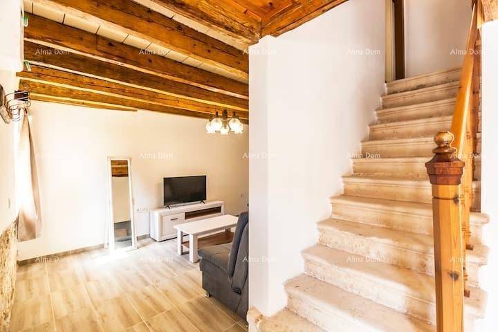 Steintreppe führt zu einem oberen Stockwerk, mit Wohnbereich und Holzbalkendecke.
