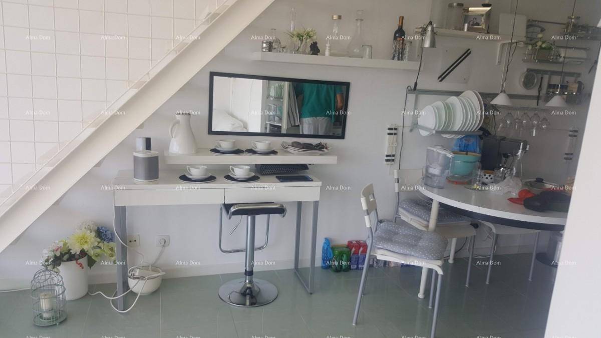 Essbereich mit kleinem Tisch, Barhocker und offener Küchenzeile unter einer Dachschräge.