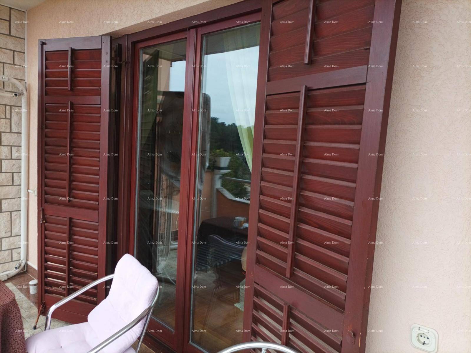 Große Glastür mit braunen Holzläden, die zu einem Balkon mit Sitzgelegenheit führt.