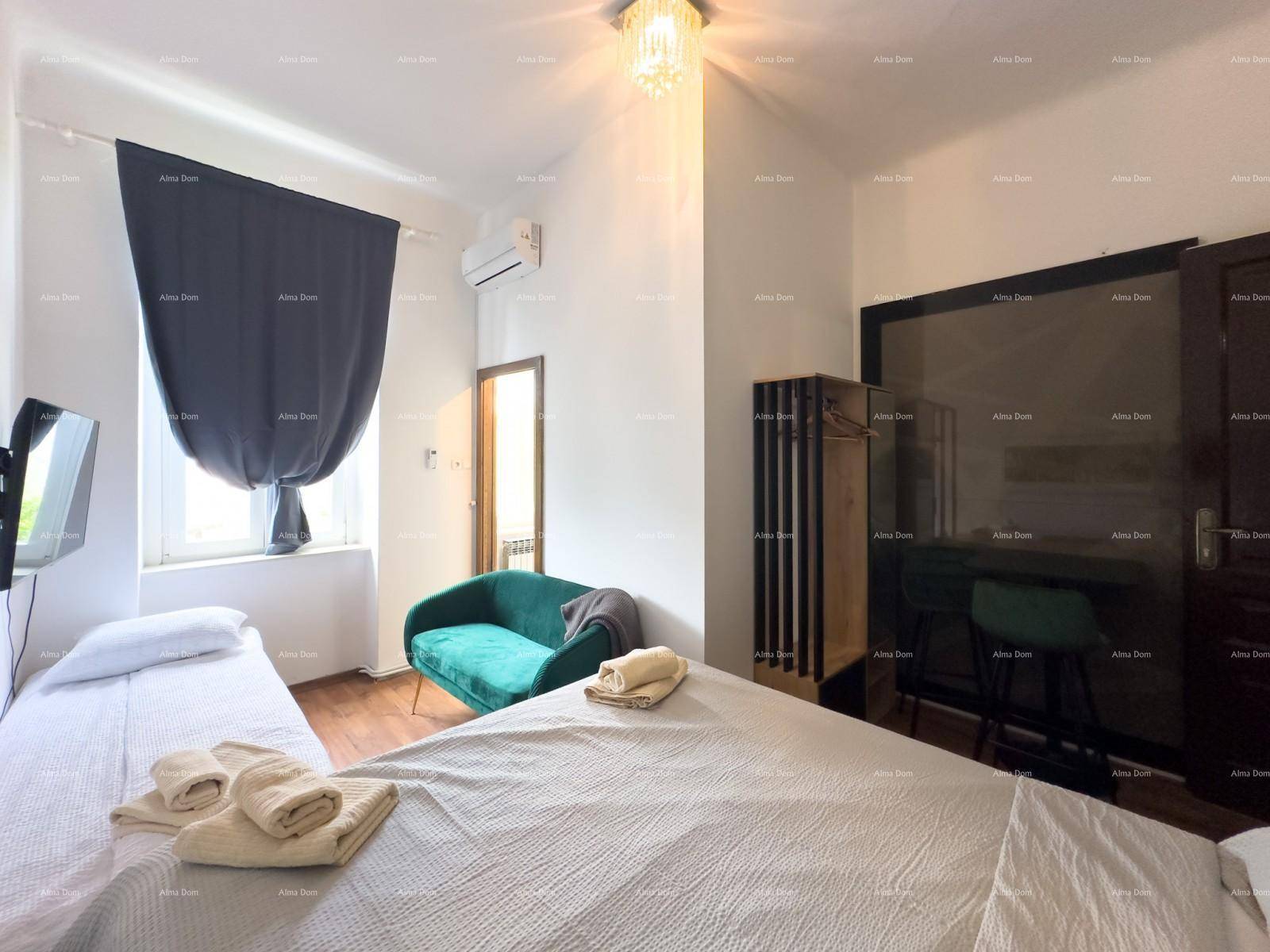 Helles Schlafzimmer mit Betten, einem grünen Sofa und einer Klimaanlage für angenehmes Raumklima.