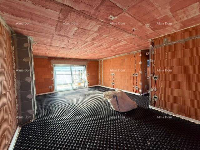 Unfertiger Wohnraum mit Ziegelwänden, Fußbodenheizungsvorbereitung und großem Fenster für viel Licht.