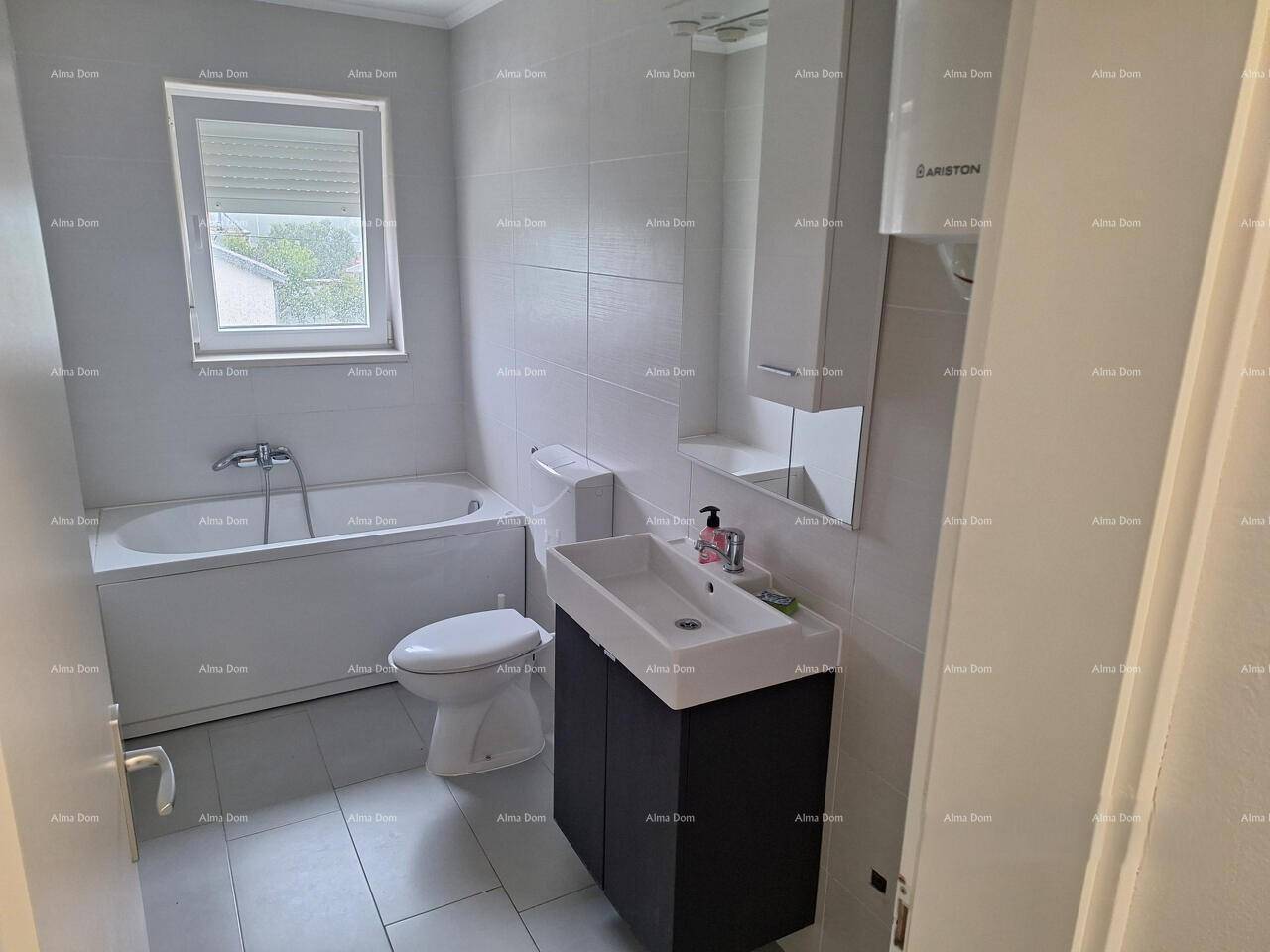 Modernes Badezimmer mit Badewanne, WC, Waschbeckenunterschrank und einem Fenster für Belüftung.