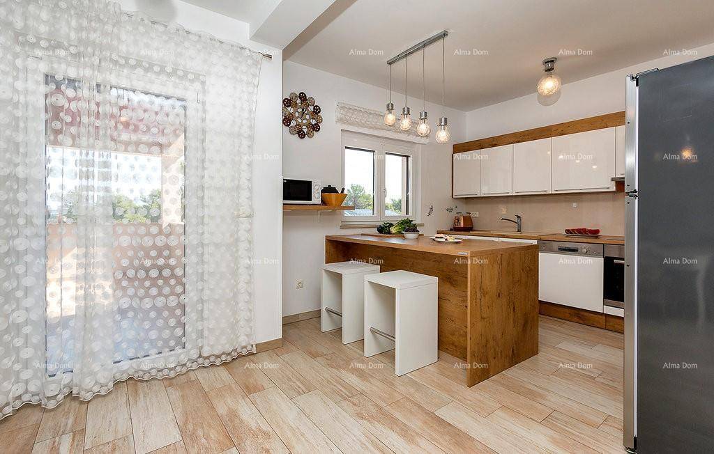 Moderne Küche mit Kücheninsel, weißen Schränken und Zugang zu einem hellen Balkon.