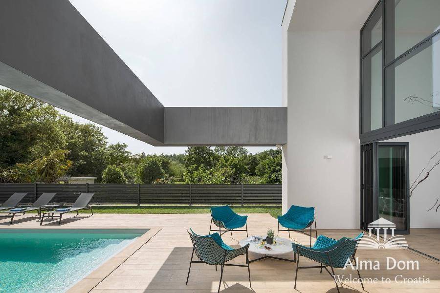Stilvolle Outdoor-Lounge mit blauen Stühlen am Pool und Blick auf die grüne Landschaft.