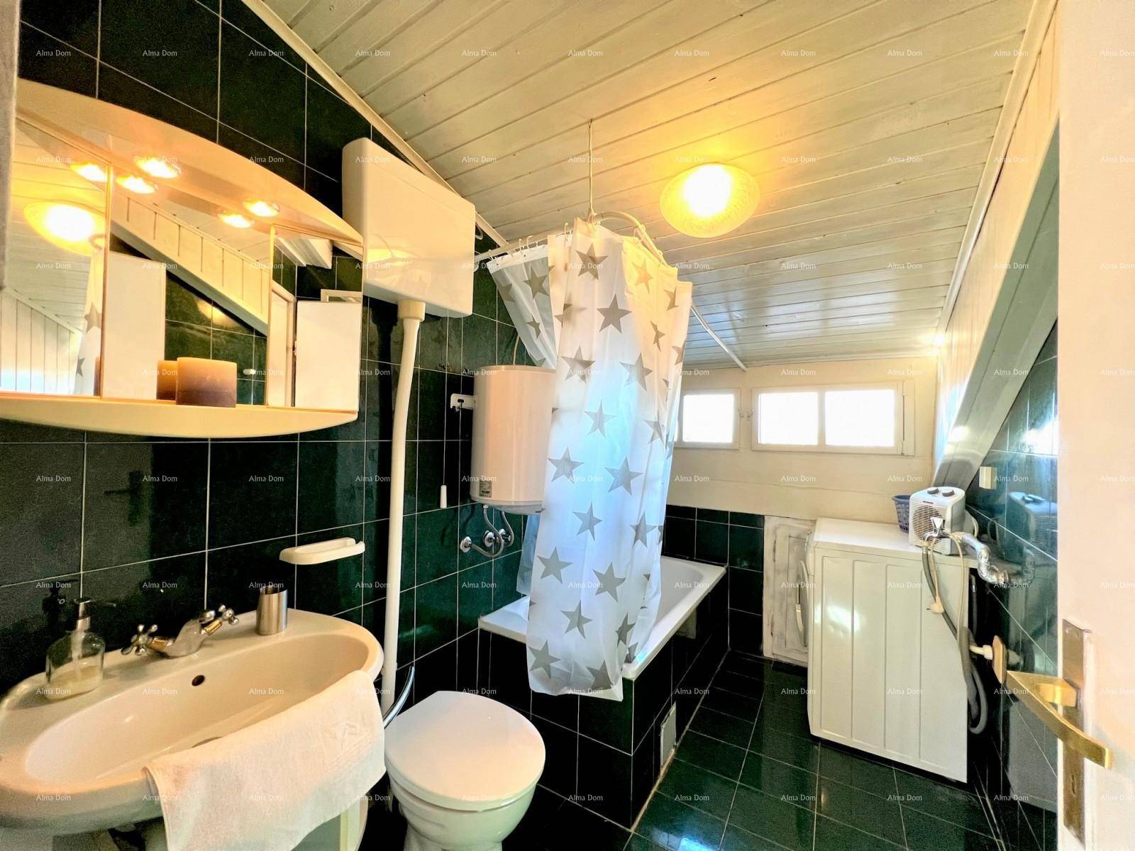 Badezimmer mit grünen Fliesen, Holzdecke, Badewanne mit Duschvorhang und Waschmaschine.
