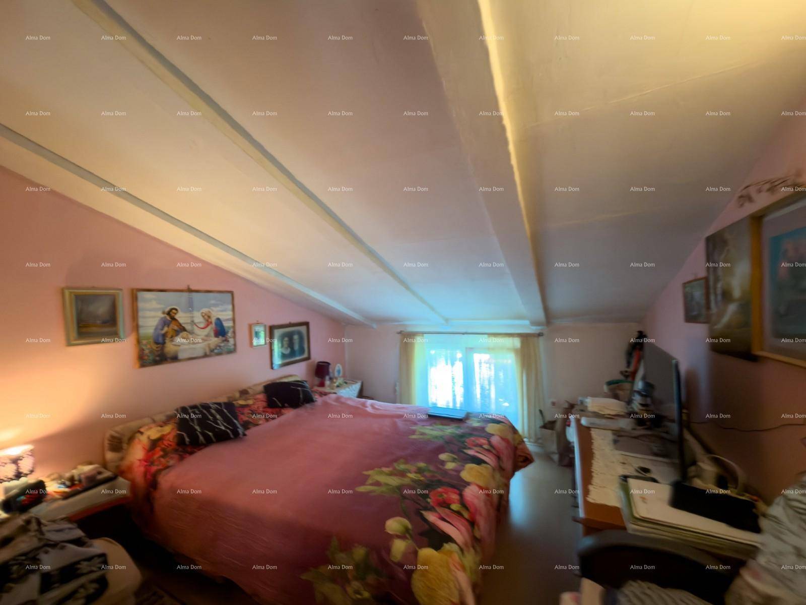 Schlafzimmer mit rosa Wänden, großem Bett, sichtbaren Deckenbalken und einem Fenster.