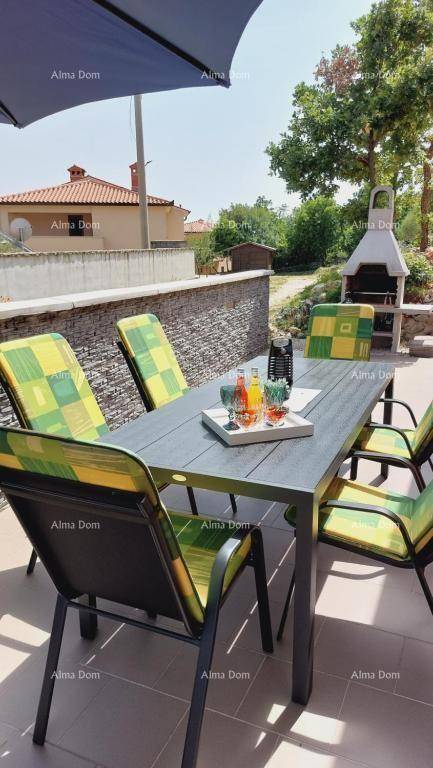 Außenterrasse mit Esstisch, Sonnenschirm und gemauertem Grillbereich.
