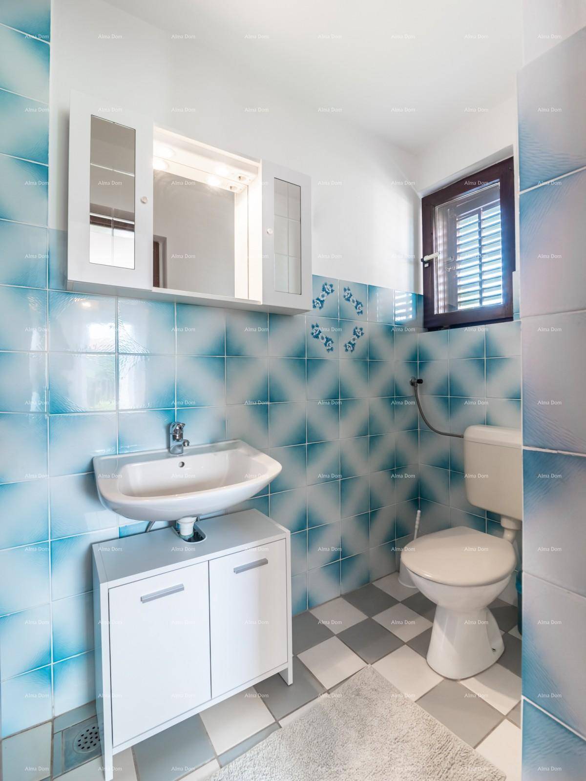 Badezimmer mit blau-weiß gemusterten Fliesen, kariertem Boden und Fenster für natürliche Belüftung.