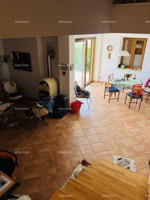 Geräumiger Wohn- und Essbereich mit Terrakotta-Fliesenboden, Holztreppe und einem Kaminofen.