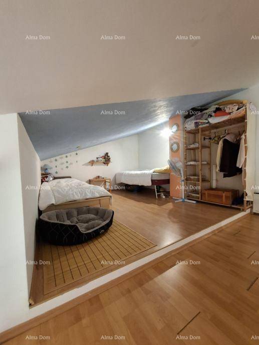 Gemütlicher Schlafbereich im Dachgeschoss mit Holzboden, schrägen Wänden und offenem Kleiderschrank.