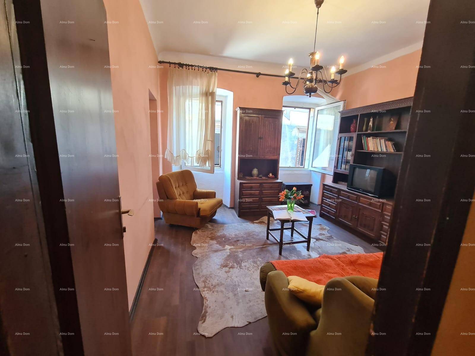 Wohnzimmer mit traditionellen Holzmöbeln, einem Kuhfellteppich und einem grünen Sofa.