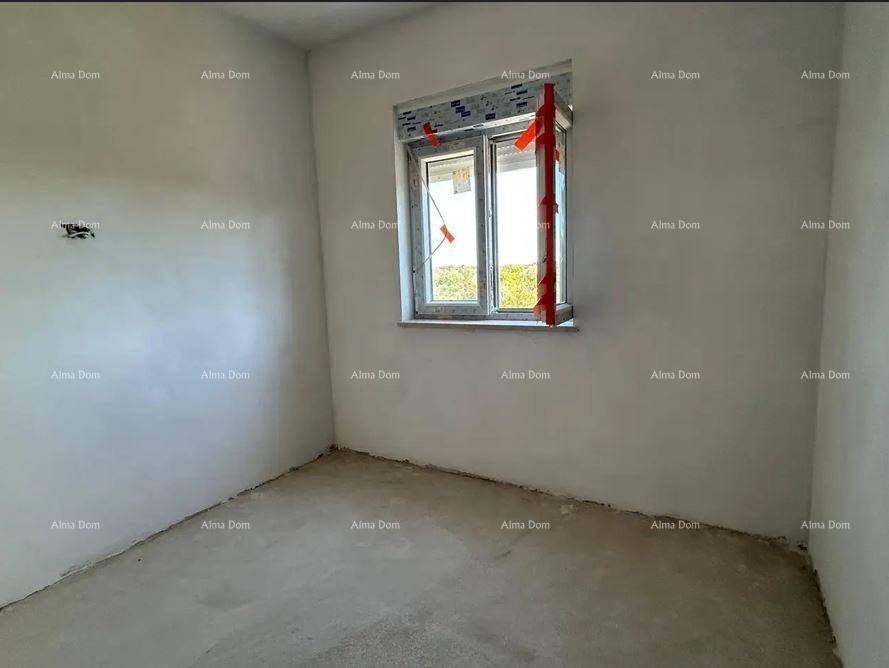 Unfertiges Schlafzimmer mit Rohbauwänden und einem Fenster, das einen Ausblick ins Grüne bietet.