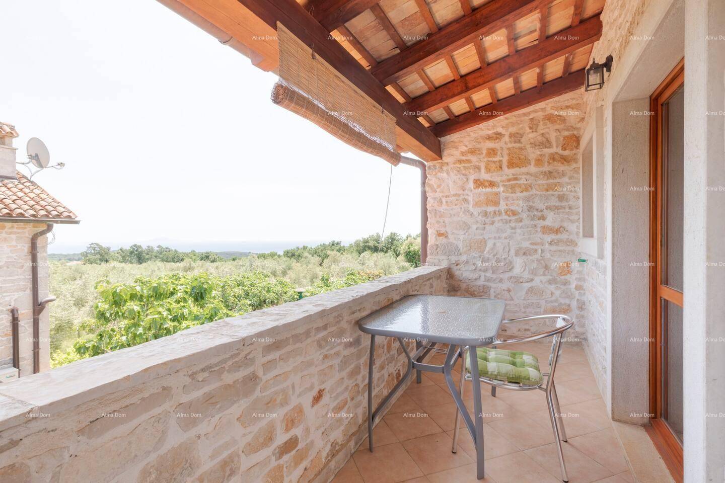 Überdachter Balkon mit Steinmauer und weitem Blick über die grüne Landschaft.