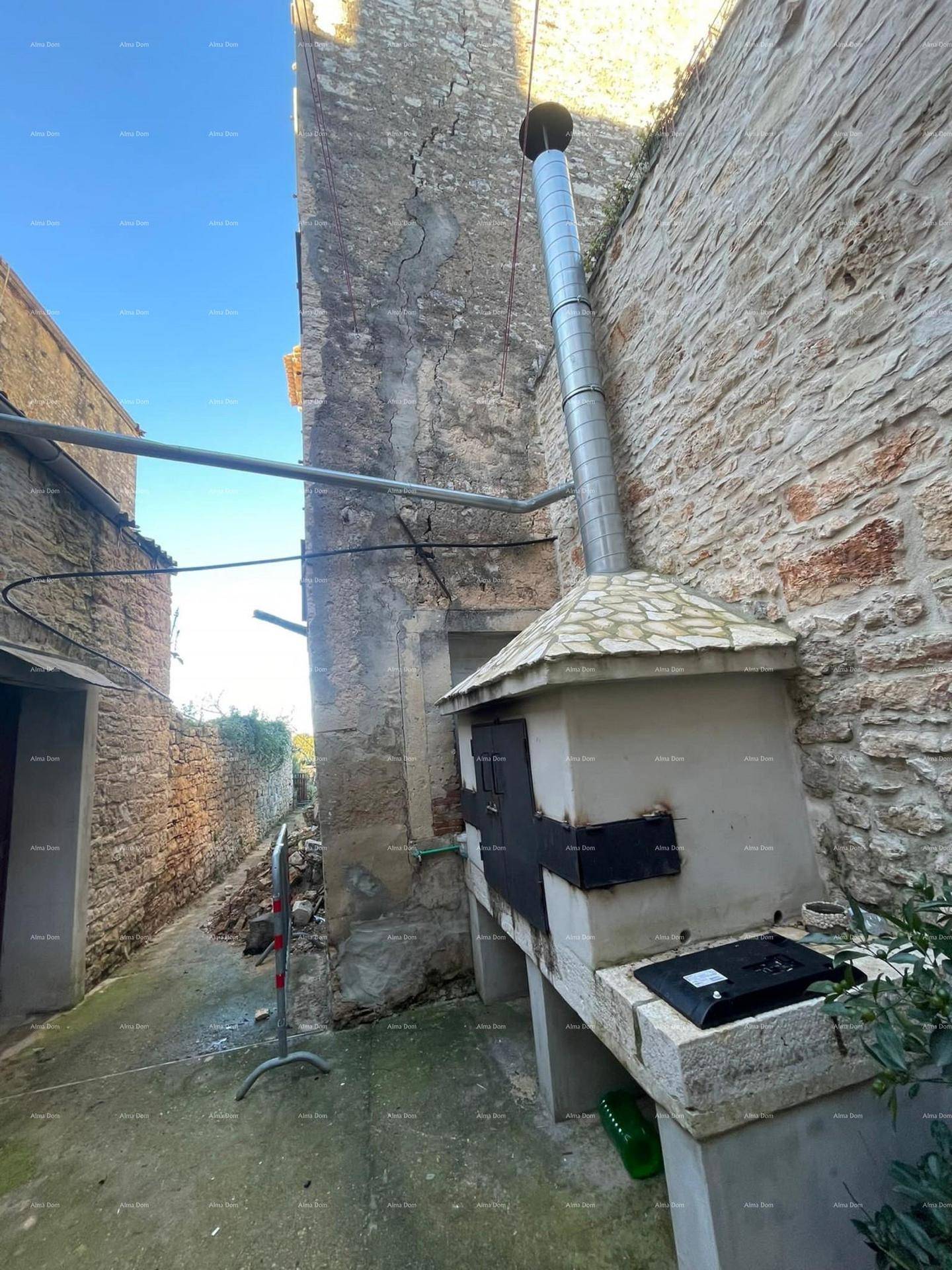 Rustikaler Außenbereich mit einem traditionellen Steinofen und Metallschornstein neben einer alten Steinmauer.