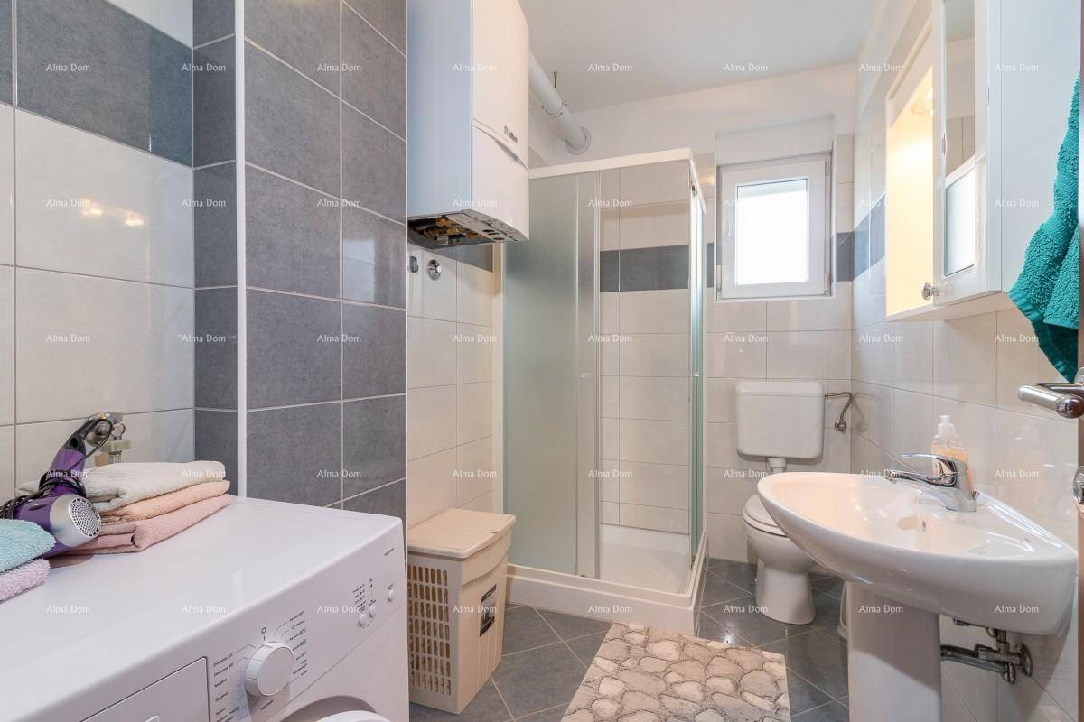 Modernes Badezimmer mit Duschkabine, Waschbecken, Toilette und Waschmaschine in Grautönen.