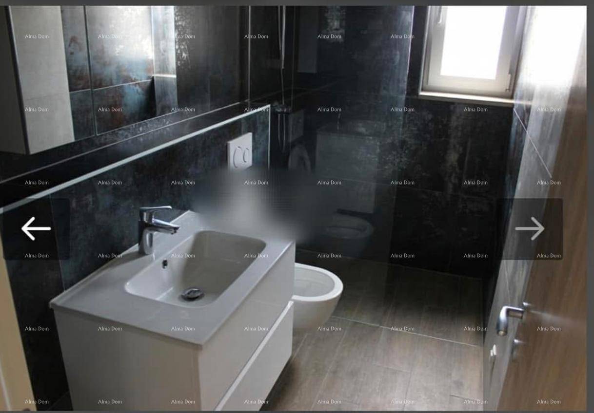 Modernes Badezimmer mit dunklen Fliesen, Waschtisch, wandhängendem WC, Bidet und Fenster.