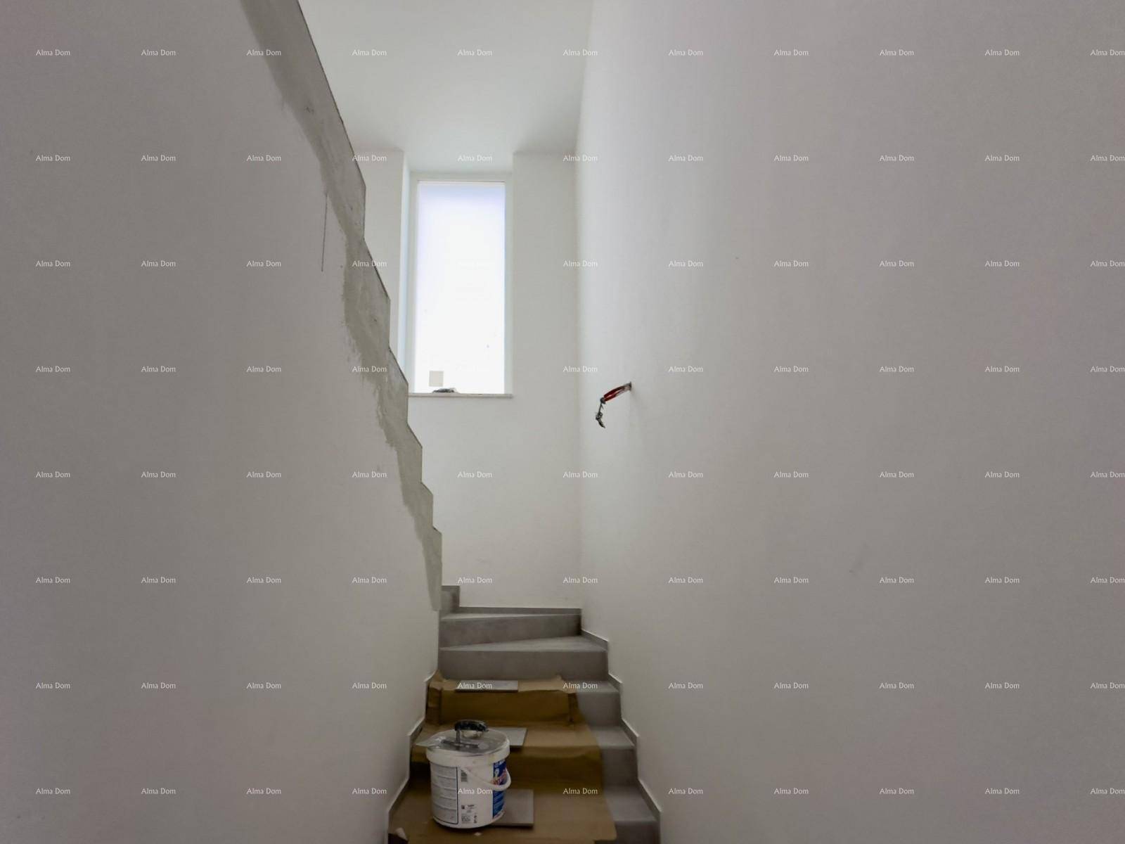Treppenaufgang im Rohbau mit einem kleinen Fenster, das natürliches Licht hereinlässt.