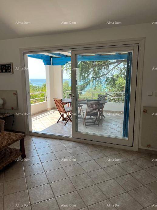 Heller Innenraum mit Fliesenboden und großem Schiebefenster zur überdachten Terrasse mit Meerblick.
