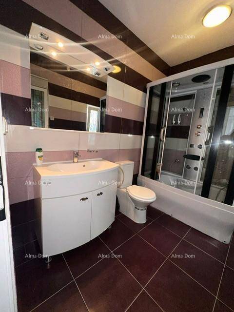 Modernes Badezimmer mit gestreiften Fliesen, Waschtischunterschrank und einer Duschkabine.