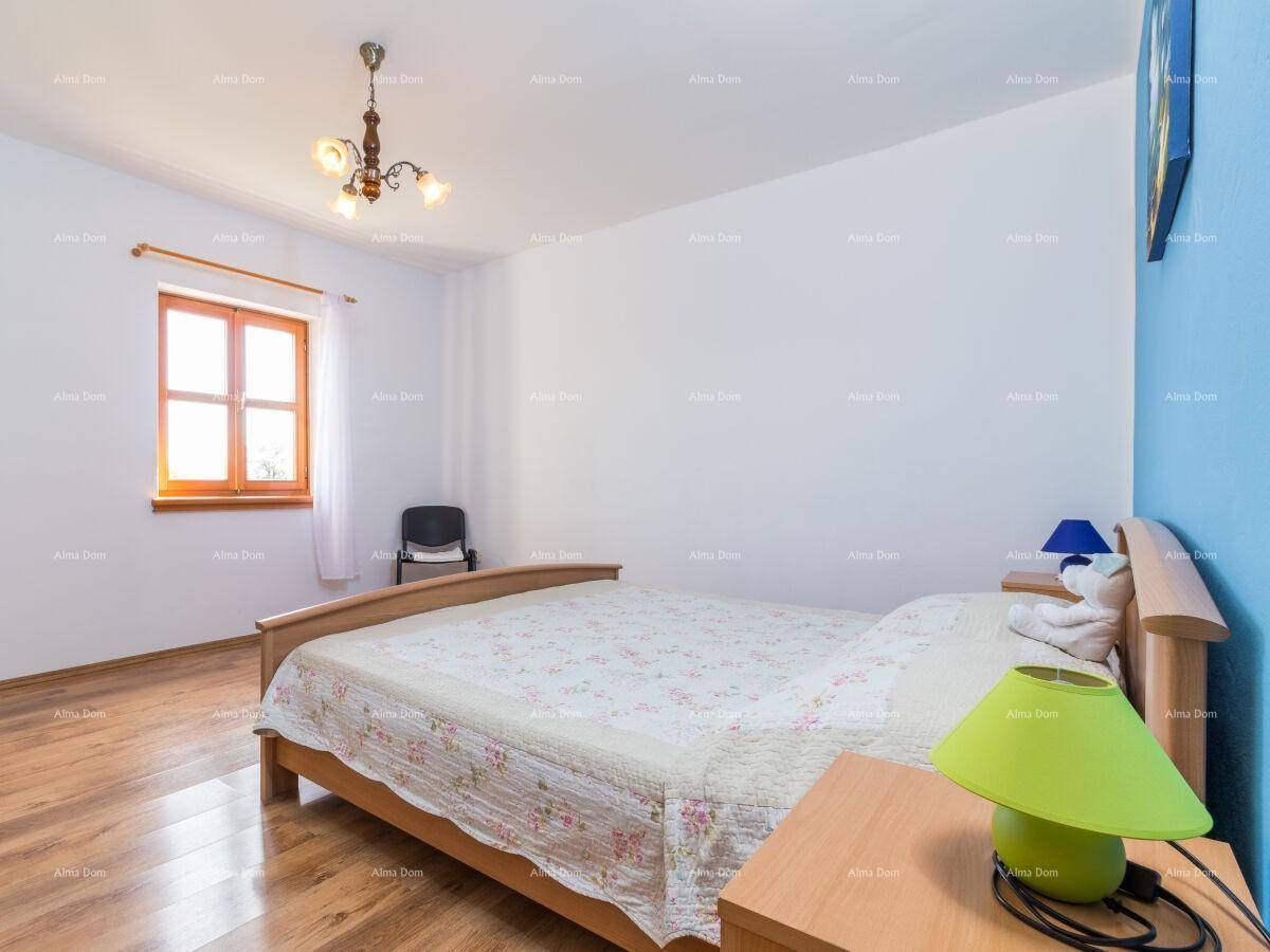 Schlafzimmer mit Holzboden, blauer Akzentwand und Fenster mit Tageslicht.