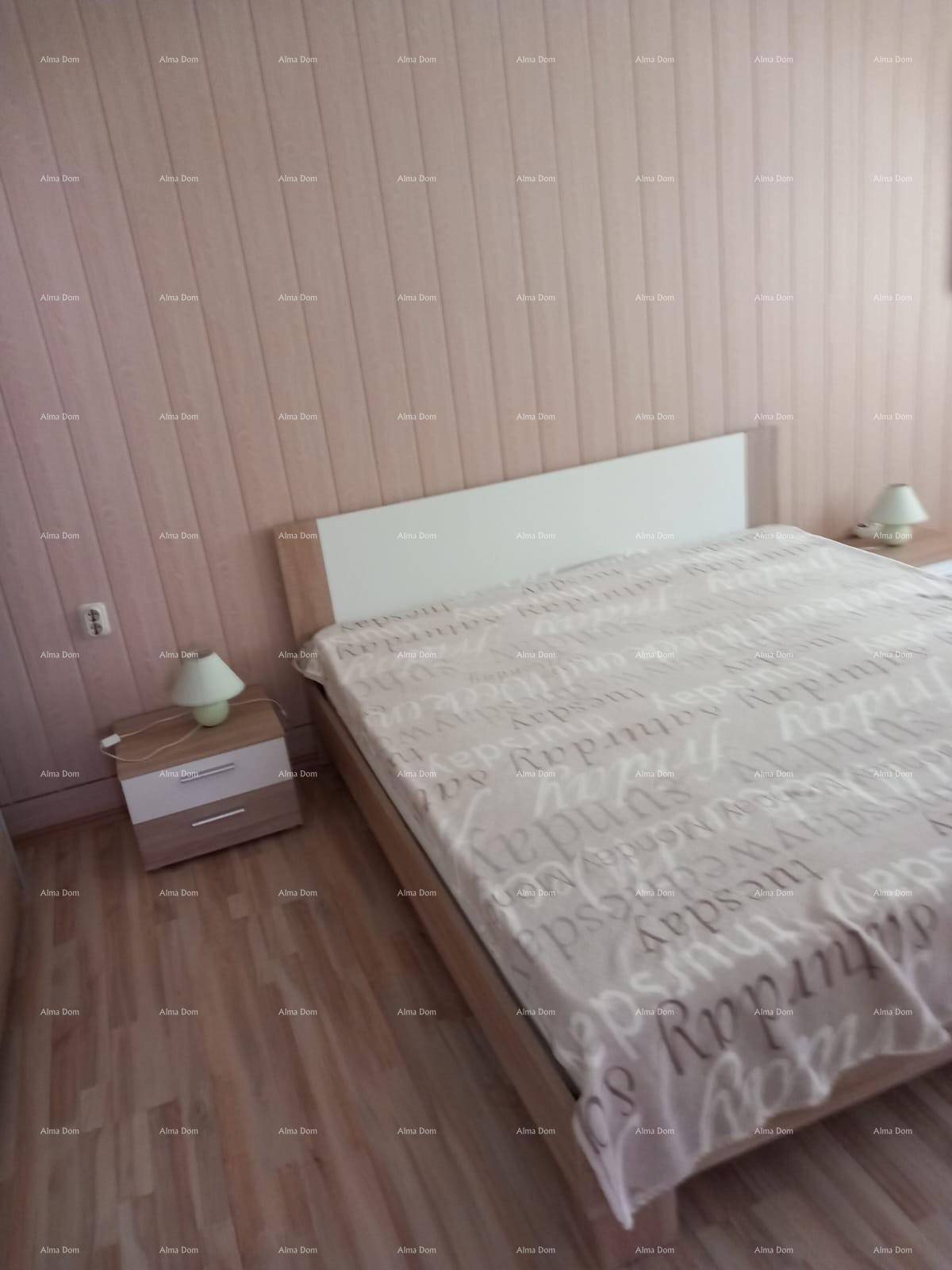 Schlafzimmer mit Doppelbett, hellen Holzpaneelen an den Wänden und Laminatboden.