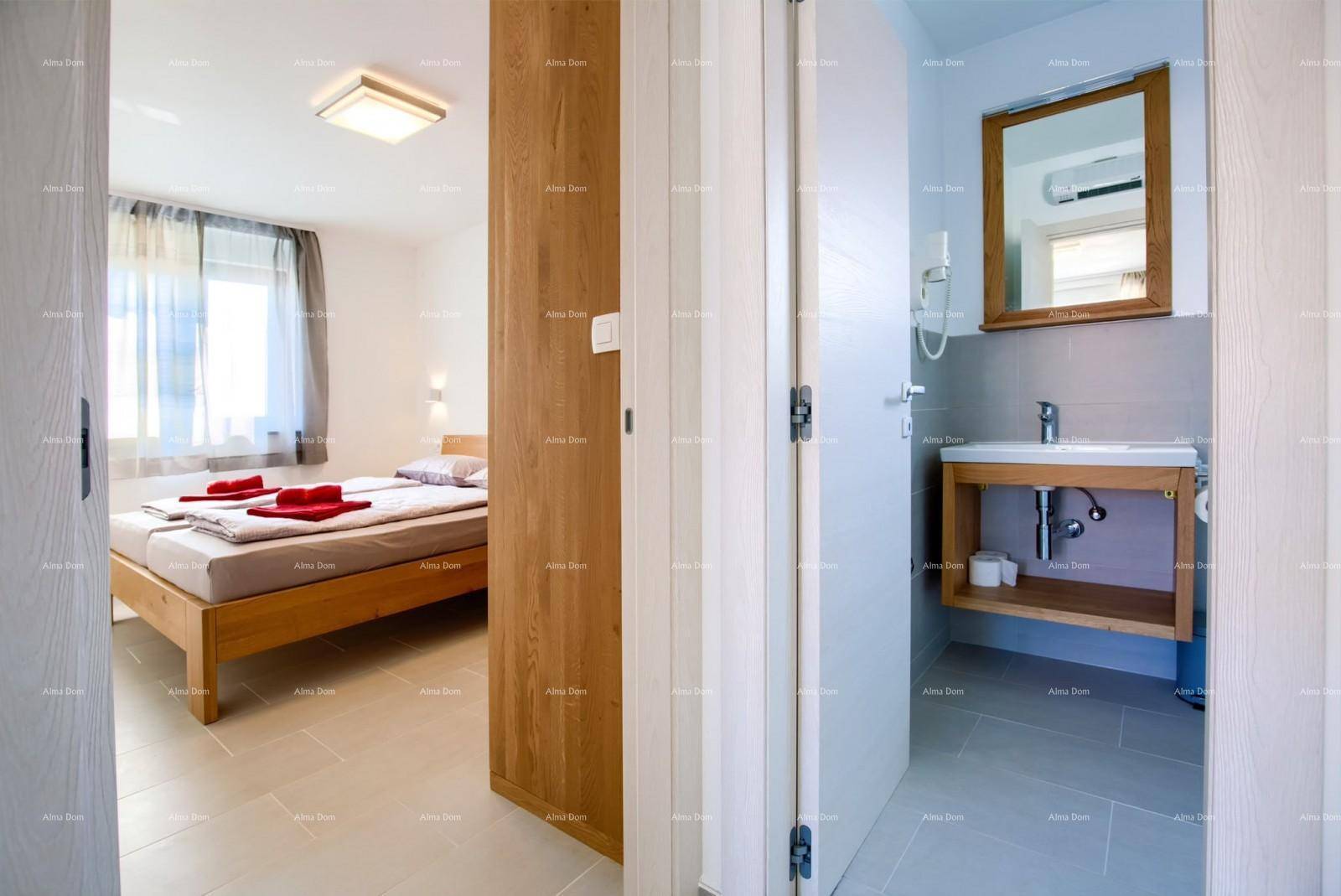 Schlafzimmer mit Doppelbett und Zugang zu einem Badezimmer mit modernem Waschtisch und Spiegel.