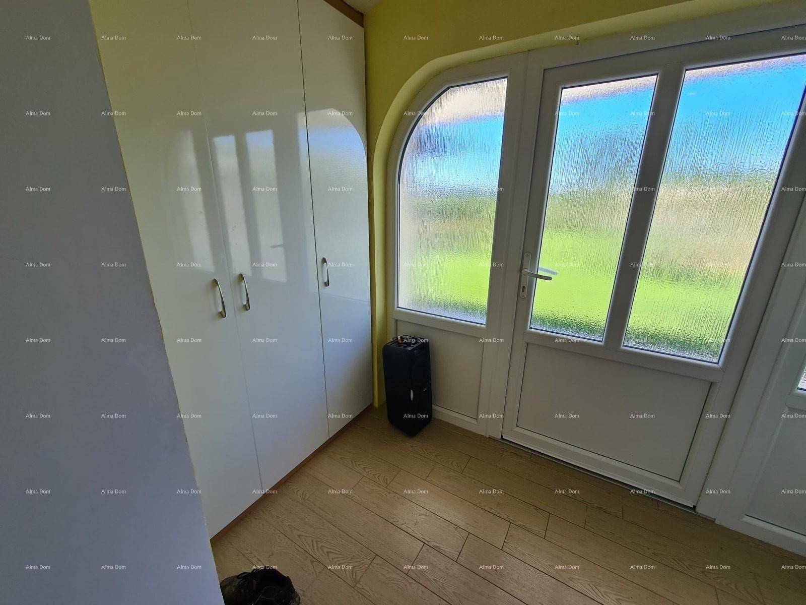 Heller Eingangsbereich mit weißem Einbauschrank und einer Glastür, die nach draußen führt.