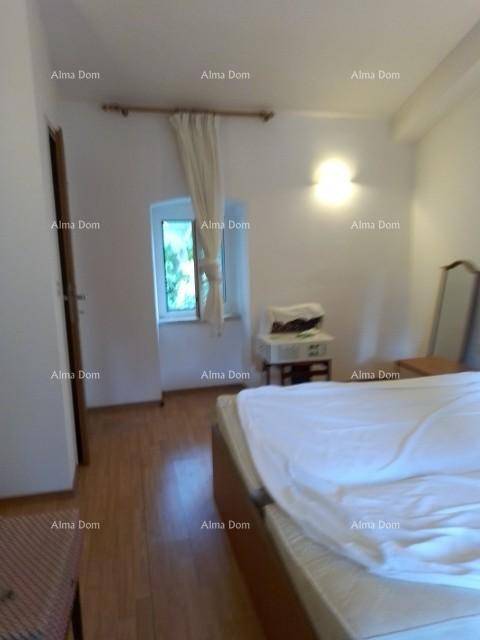 Schlafzimmer mit Bett, kleinem Fenster mit Vorhängen und einem Nachttisch auf Holzboden.