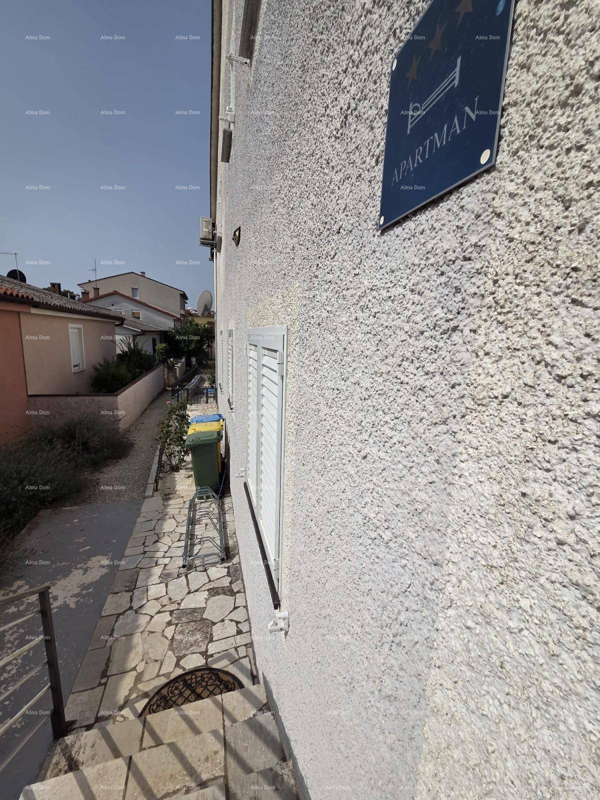 Seitenansicht des Gebäudes mit weißer Fassade, Fensterläden und einem Hinweisschild.