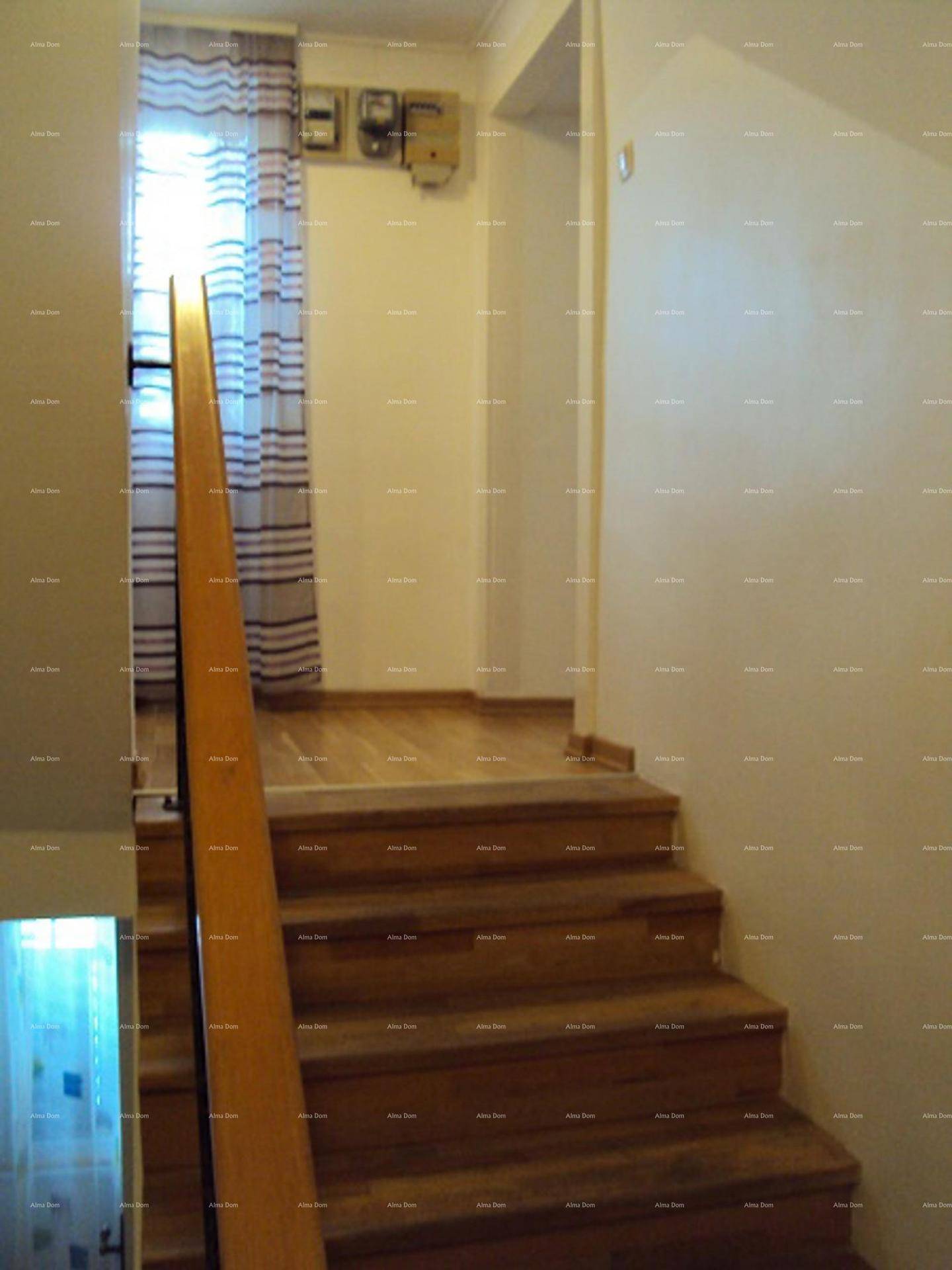 Holztreppe mit Geländer und einem Fenster, das natürliches Licht hereinlässt.