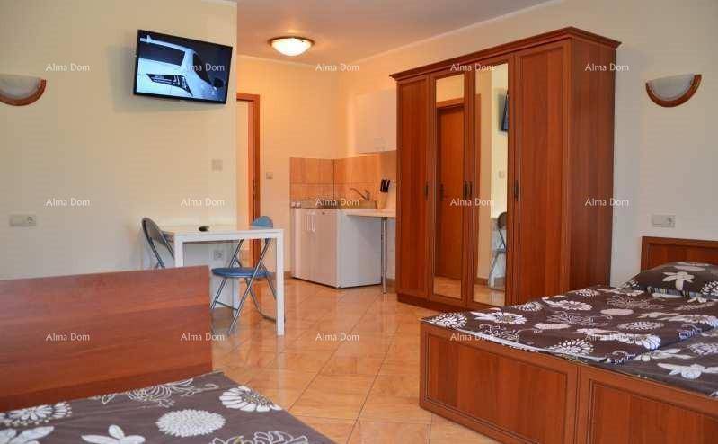 Schlafzimmer mit zwei Einzelbetten, Kleiderschrank und kleiner Küchenzeile im Raum.